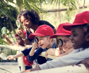 kids use magnifying glasses on a field trip
